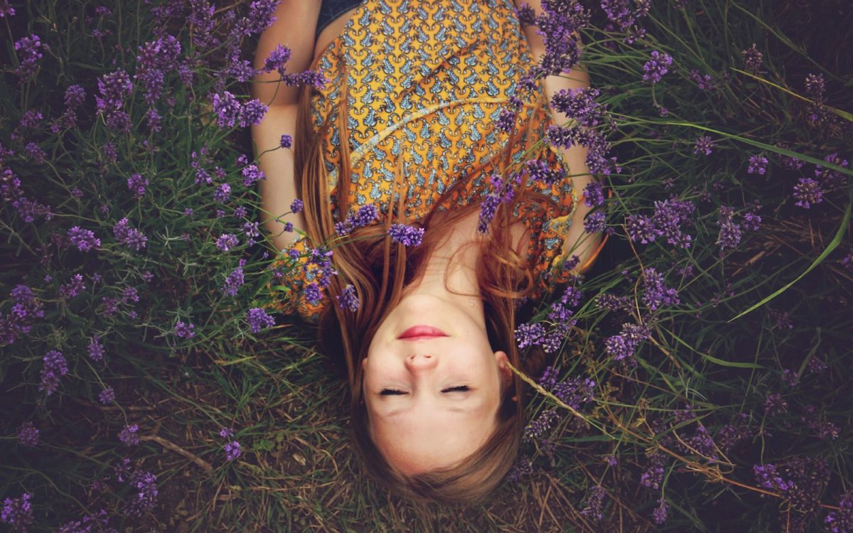woman in yellow and teal top sleeping beside lavenders