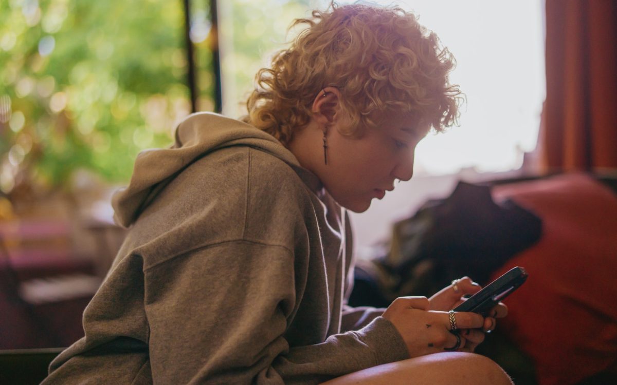 Portrait of a nonbinary autistic person using their mobile phone indoors